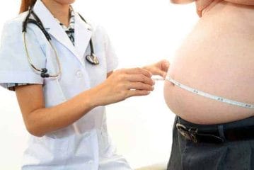医者は肥満男の腹囲を測る