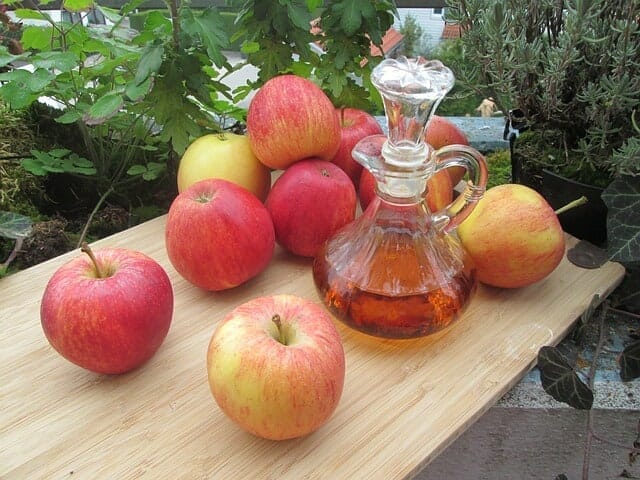 テーブルの上に置かれた新鮮なリンゴとリンゴ酢のボトル
