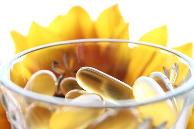 ガラスの中の丸薬、背景に黄色の花