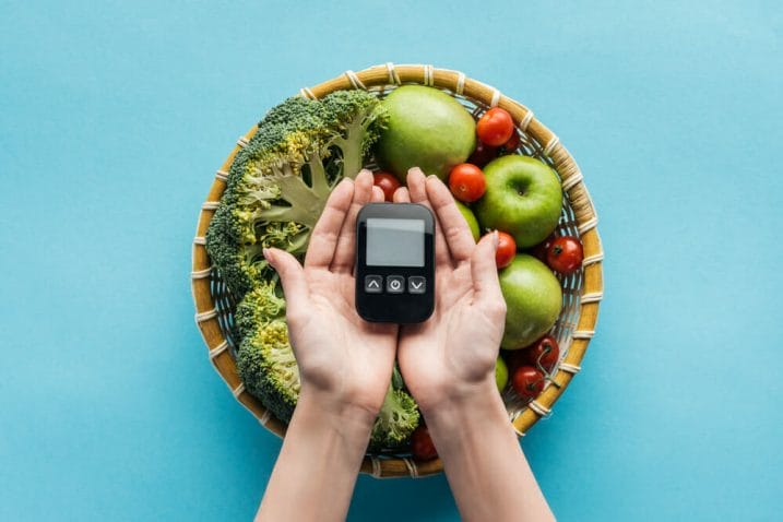 野菜や果物が盛られたボウルの横には、携帯型の血糖値測定器が置かれている