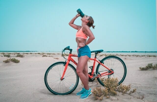 自転車で走った後、ボトルの水を飲む女性